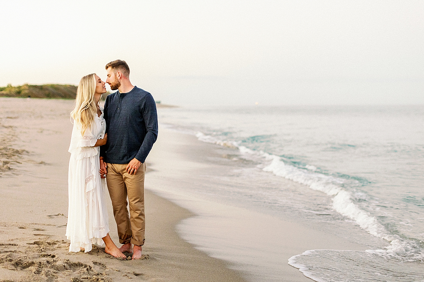 Couple looking into each others eyes as the ocean water comes in on the beach Jupiter Engagement Photography captured by South Florida Engagement Photographer Erika Tuesta Photography