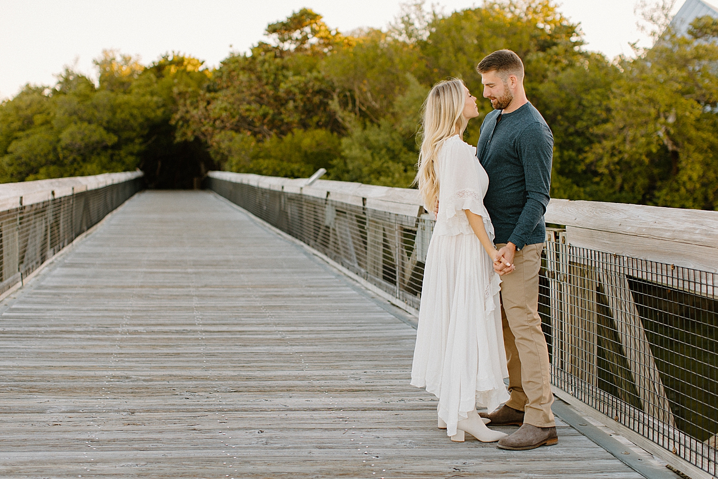 Couple hold hands and look into each others eyes on wooden bridge Jupiter Engagement Photography captured by South Florida Engagement Photographer Erika Tuesta Photography