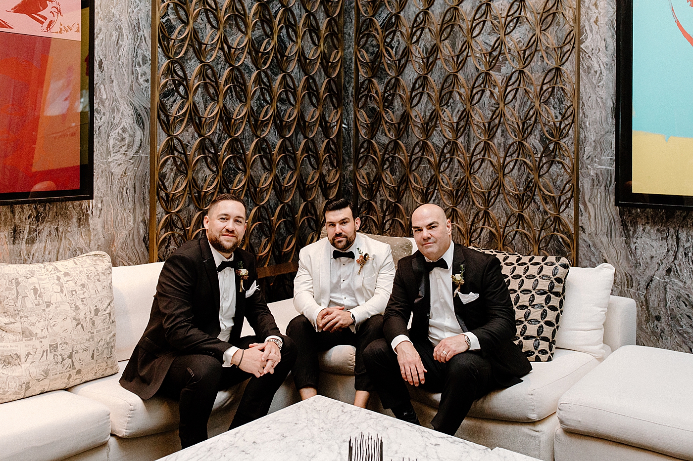 Groom and groomsmen sitting on love couch after getting ready Modern Elegant Wedding at The W South Beach captured by South Florida Wedding Photographer Erika Tuesta Photography