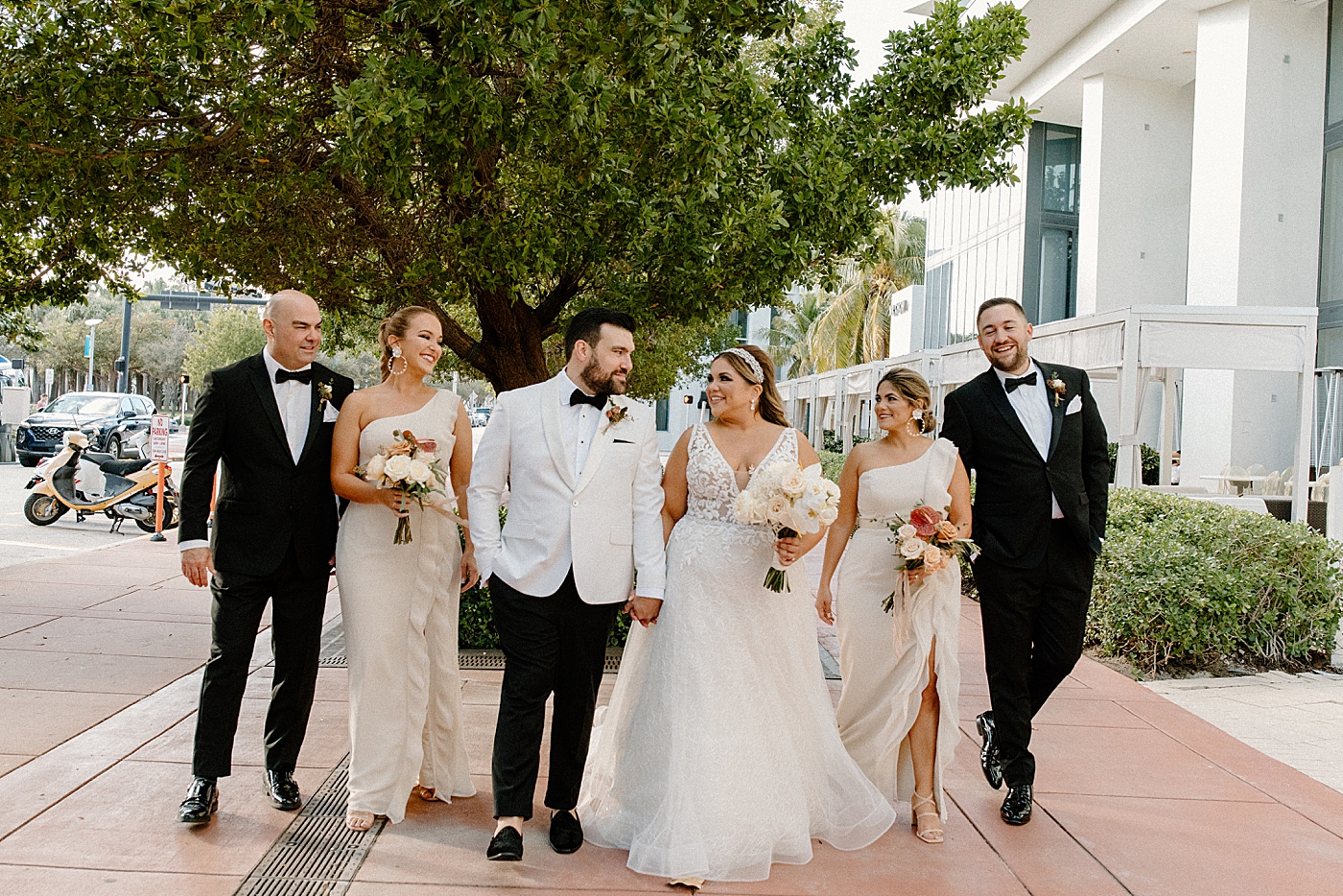 Bride and Groom holding hands and walking together with Wedding party following and watching Modern Elegant Wedding at The W South Beach captured by South Florida Wedding Photographer Erika Tuesta Photography