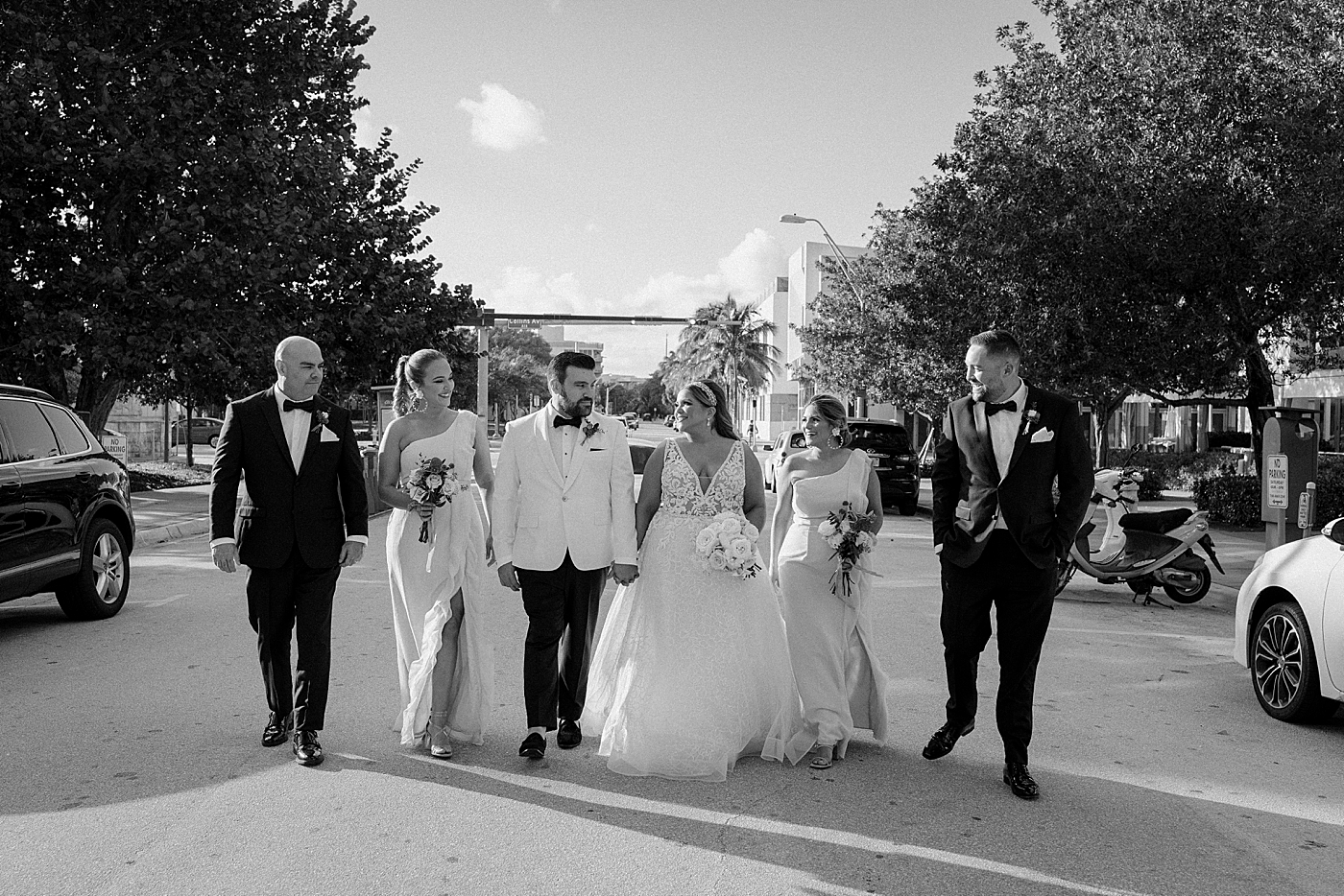 B&W Bride and Groom holding hands with wedding party watching Modern Elegant Wedding at The W South Beach captured by South Florida Wedding Photographer Erika Tuesta Photography