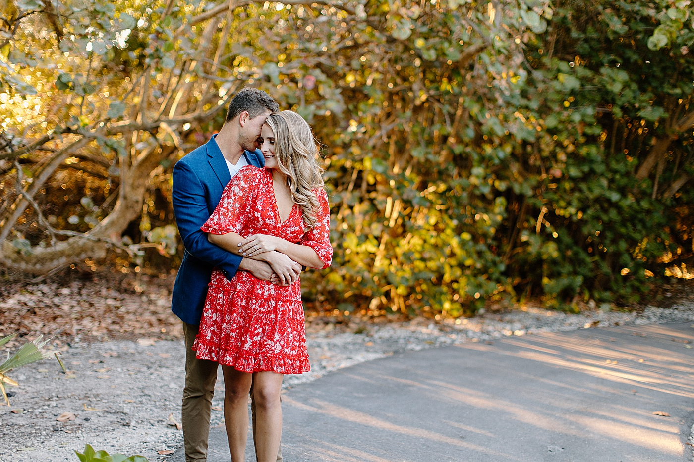 Man hugging woman from behind on path in park Red Reef Park Engagement Photography captured by South Florida Engagement Photographer