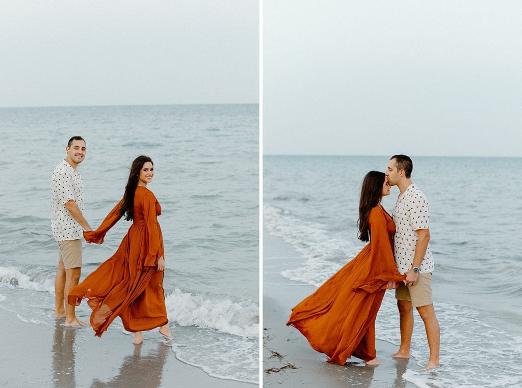 Couple holding hands entering ocean water on the beach