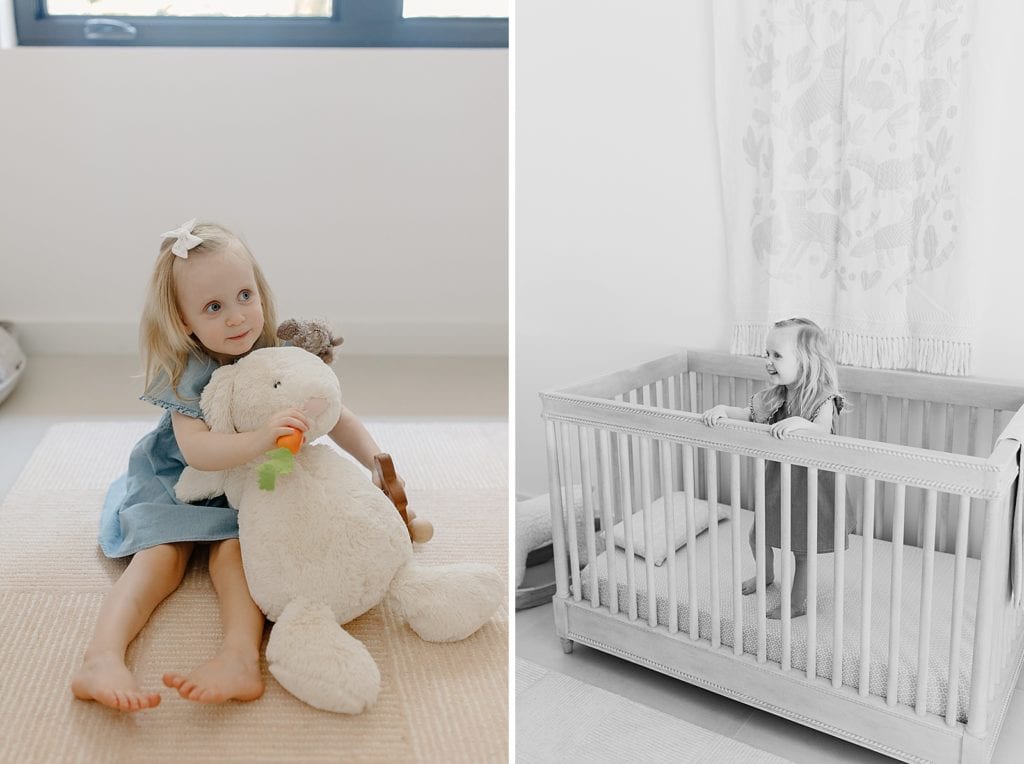 Little girl holding stuffed rabbit and standing in crib