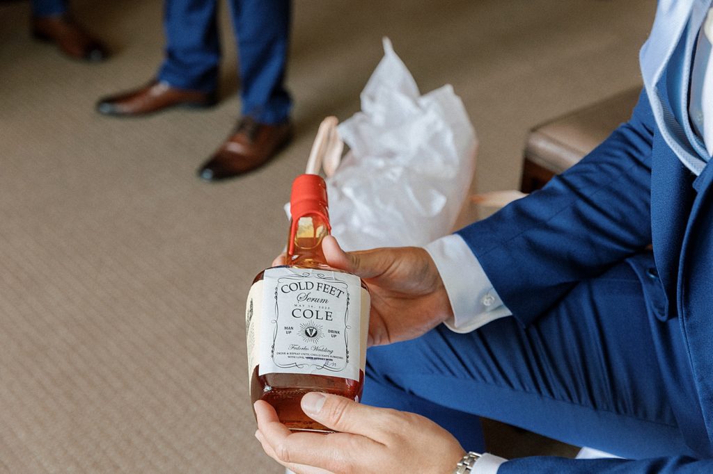 Groom holding liquor bottle after getting ready