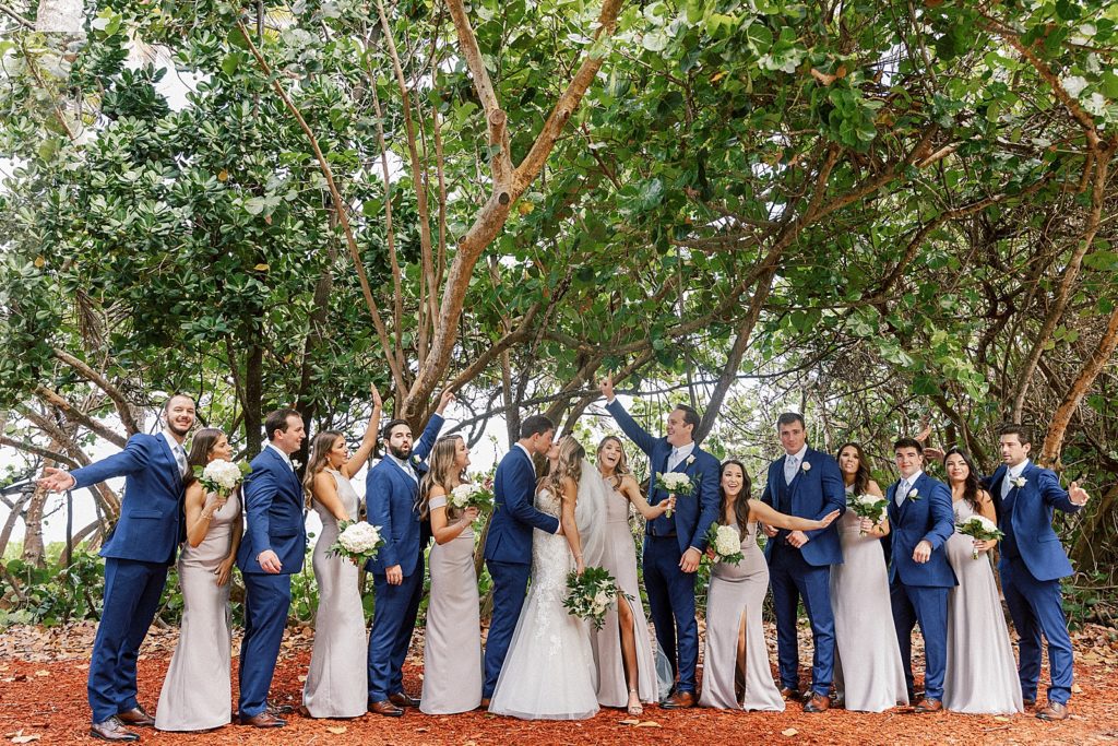 Bride and Groom kissing with Wedding party celebrating