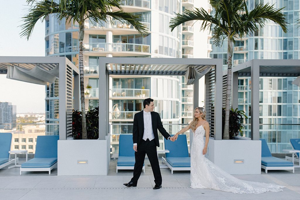 Groom holding Bride's hand and leading through hotel outdoor pool area