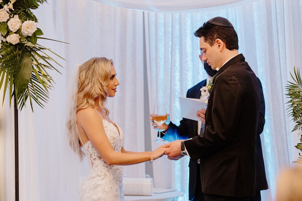 Bride and Groom hand in hand with officiant holding wine for Ceremony