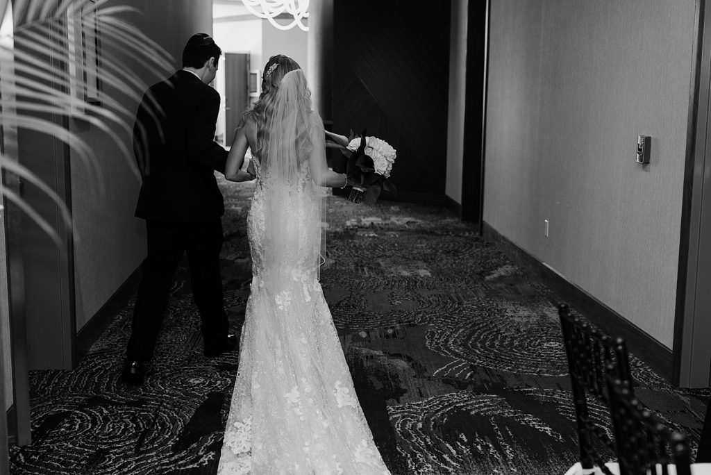 B&W Bride and Groom walking together down hotel hallway together
