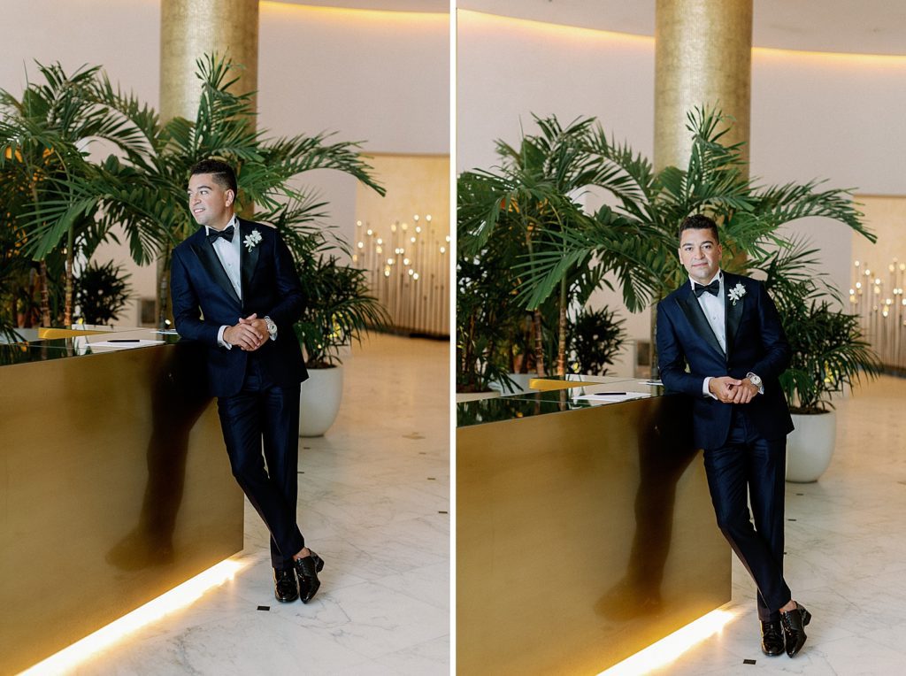 Groom leaning on gold front desk check-in for portraits