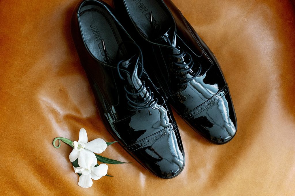 Detail shot of boutonniere and black reflective shoes 