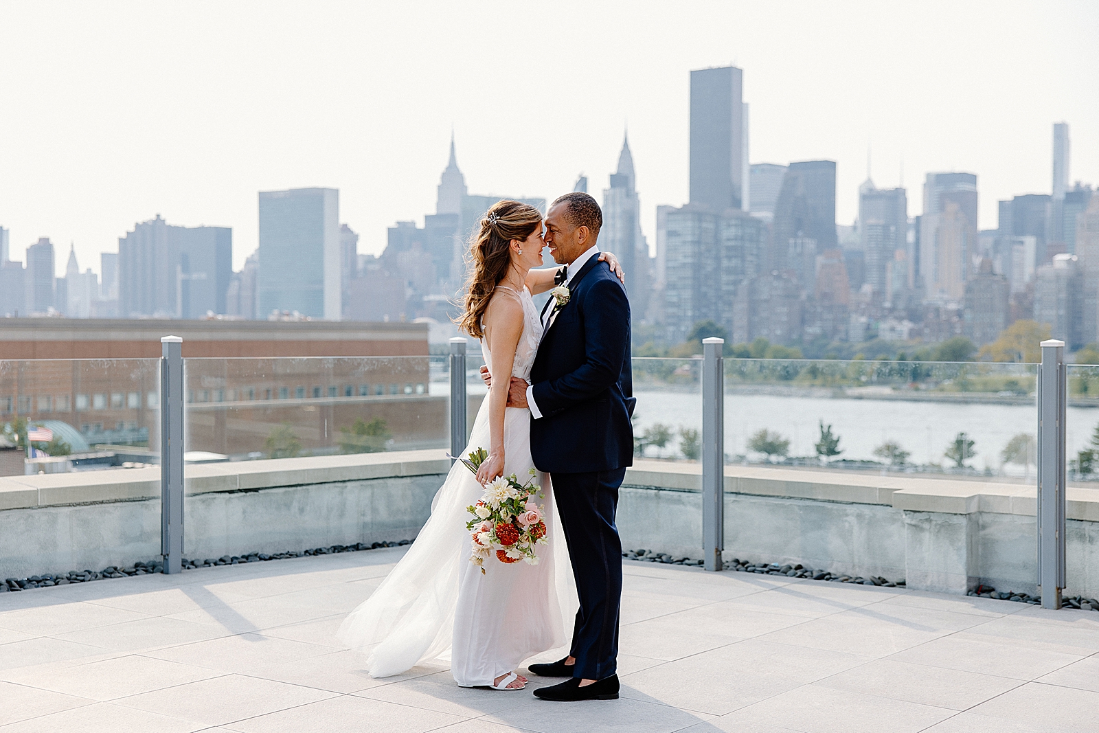 Bride and Groom holding each other face to face with Empire state and Chrysler building across the east river