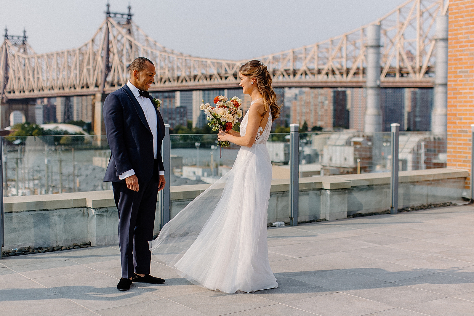Bride and Groom facing each other with Bride holding bouquet with Queensboro bridge in the background