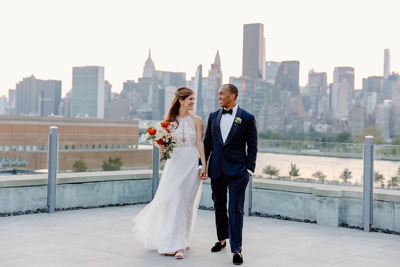 Bride and Groom holding hands and looking at each other with Chrysler and Empire State Building view behind them
