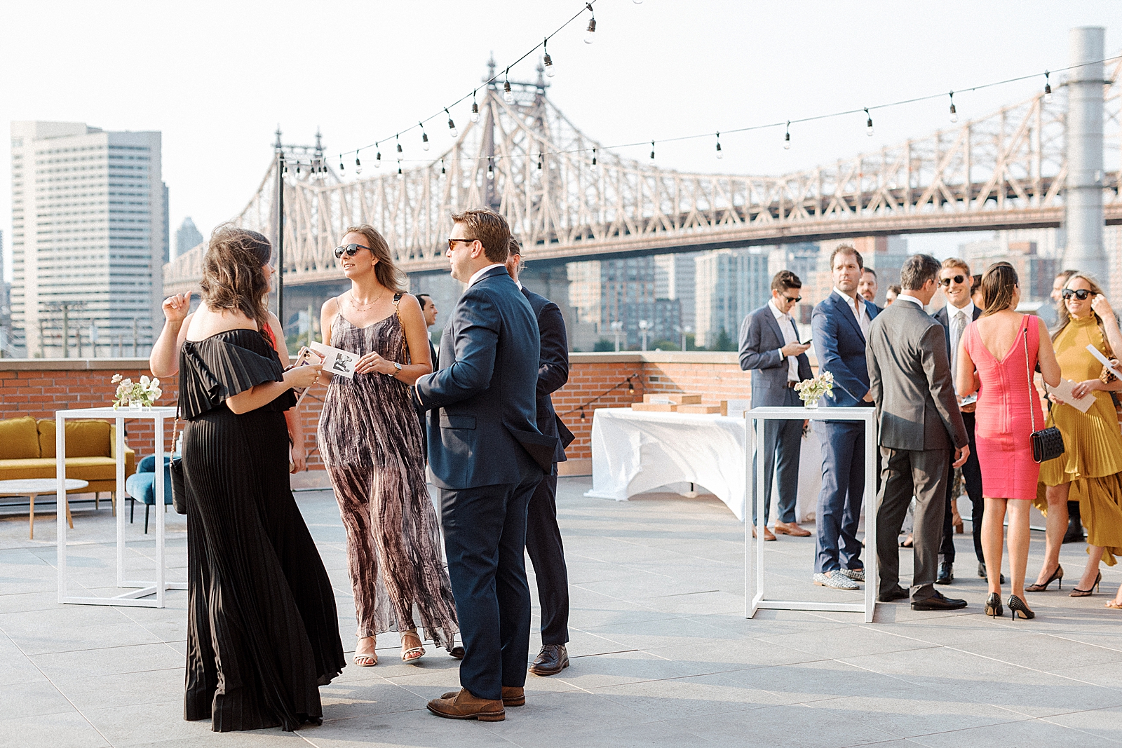 Candid shot of guests at cocktail hour with Queensboro bridge in the background