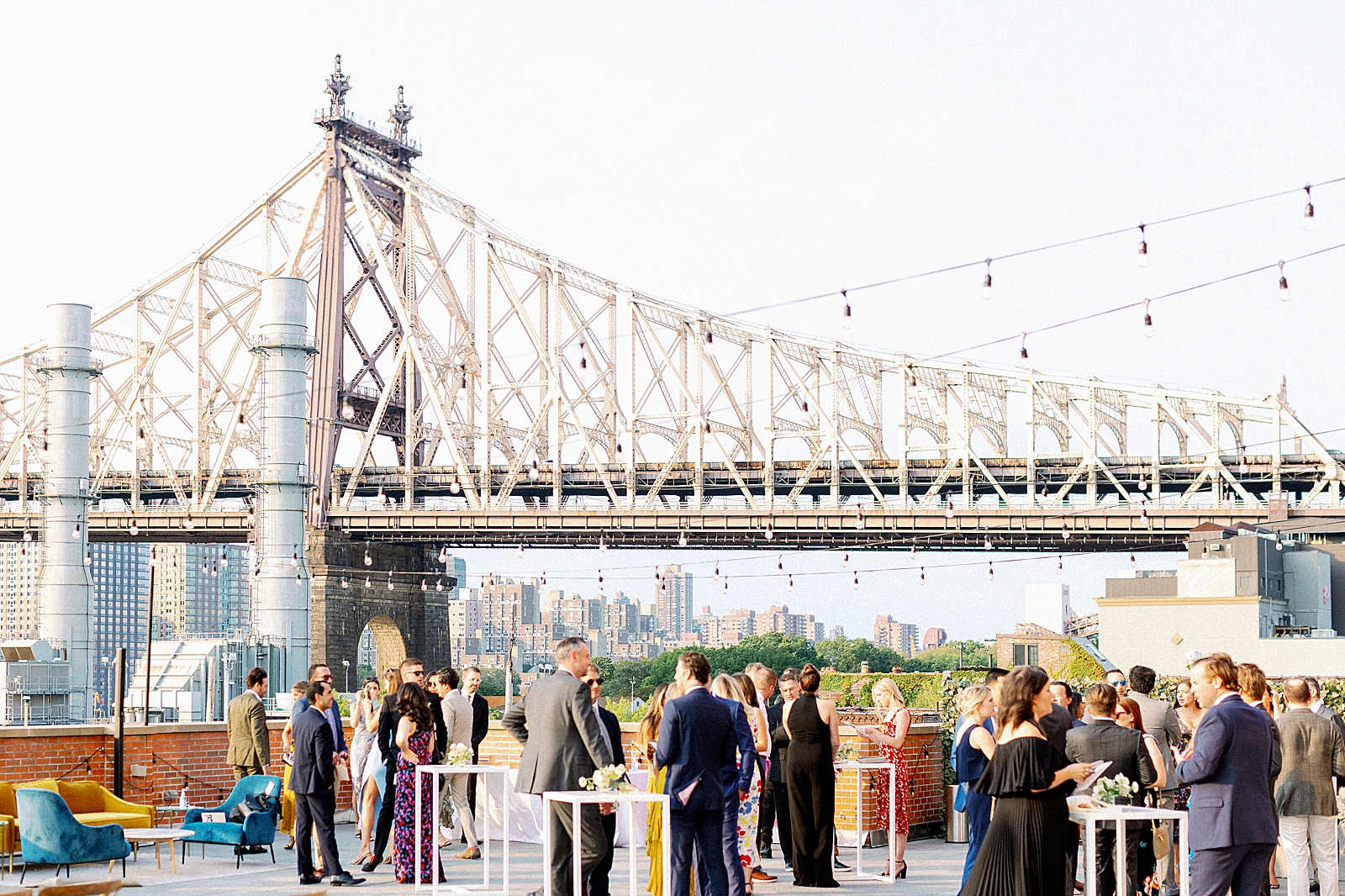 Candid shot of guests at cocktail hour with Queensboro bridge in the background