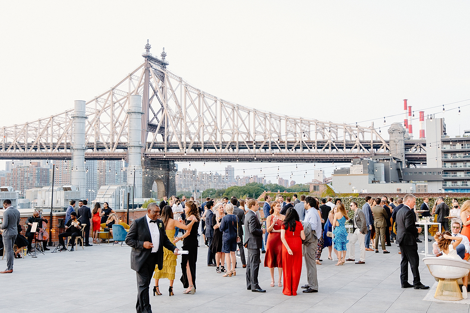 Wide shot of guests socializing at cocktail hour with string quartet playing in Long Island City