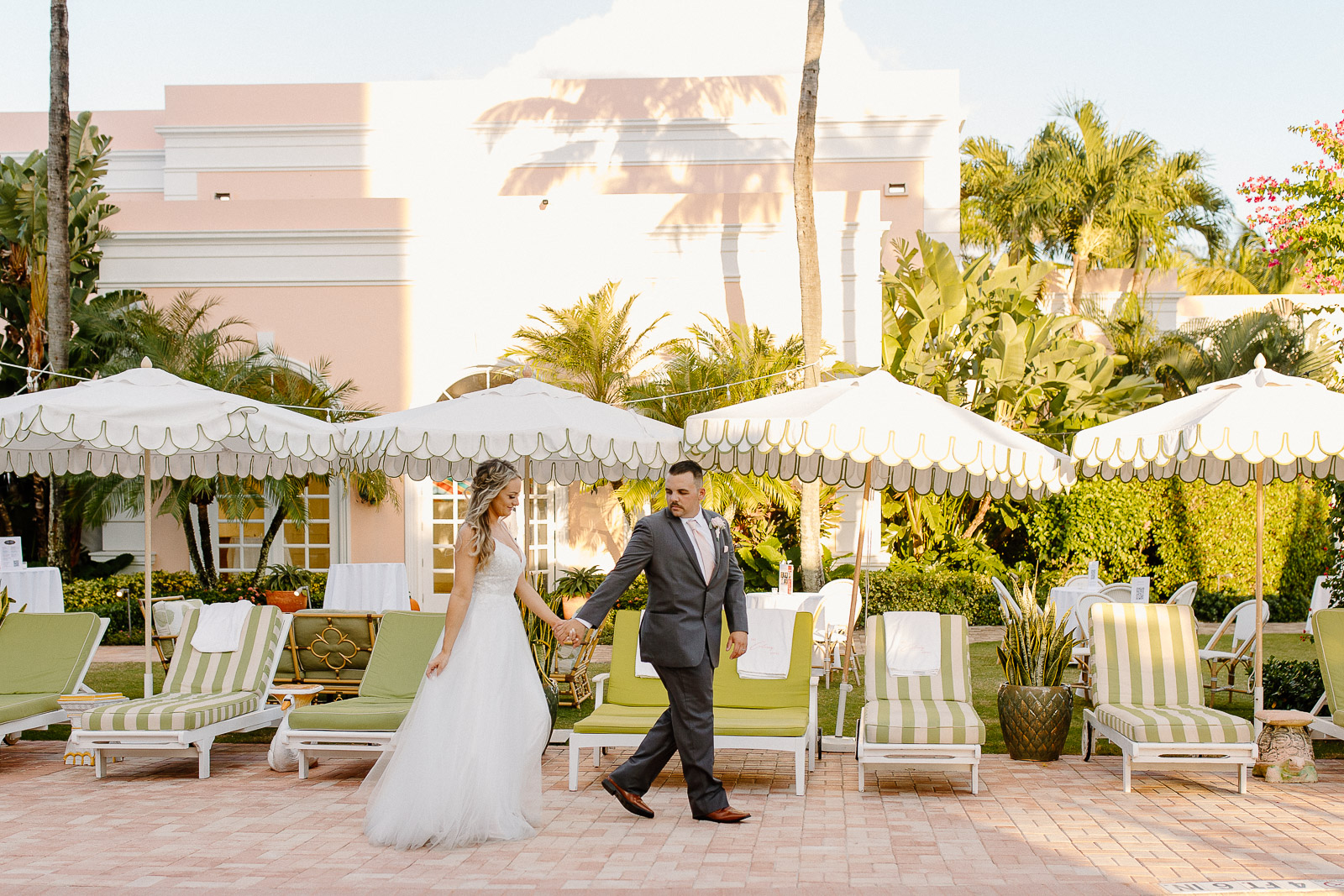 bride and groom walking near the pool at The Colony Palm Beach Hotel