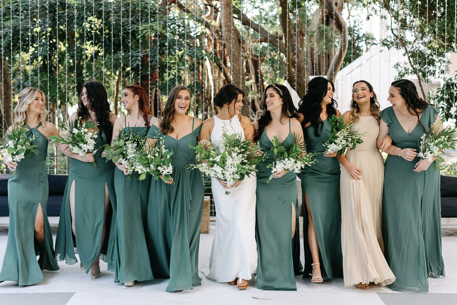 bridesmaids walking in green dresses holding bouquets at Baker's Cay Resort
