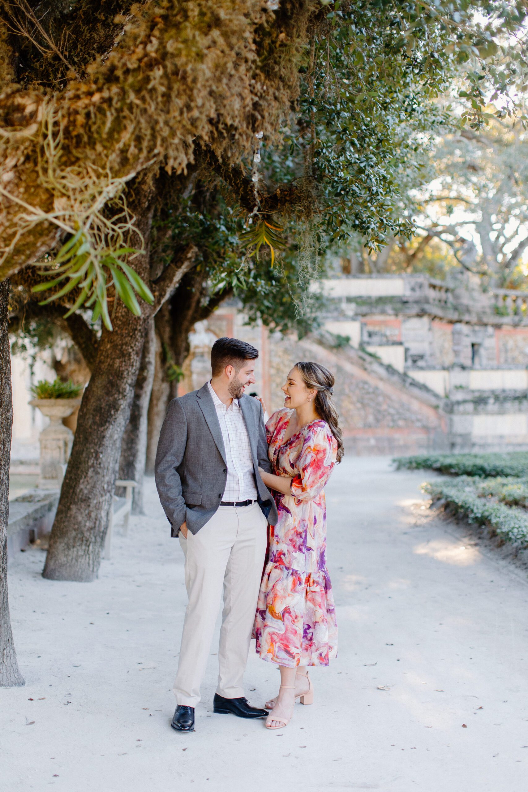 Couple smiling and walking holding hands at Vizcaya Museum and gardens, miami engagement photograpgher 